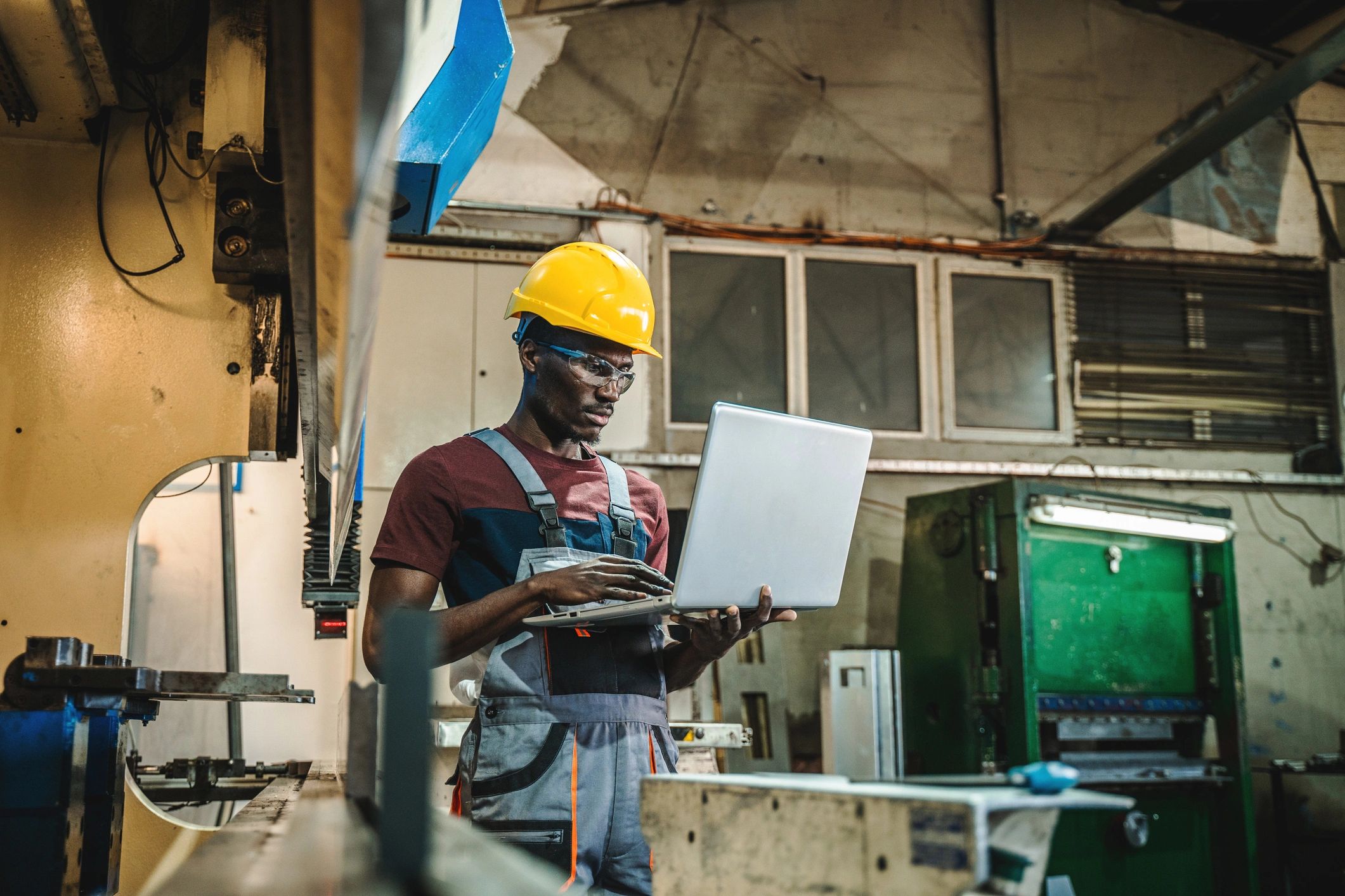Engineer using a laptop while inspecting industrial equipment